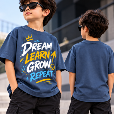 Boy wearing a navy blue boys graphic printed tee with Dream Learn Grow Repeat inspirational text on front